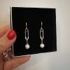 Mini Safetypins örhängen i rostfritt stål med sötvattenspärlor och säkerhetsnålsdesign i silverfärg.