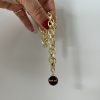 Guldfärgat halsband i mässing med coin-berlock och texten "fuck off".