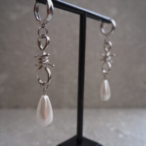 Barbed wire earrings i rostfritt stål på modell, kombinerar rockig och romantisk stil.