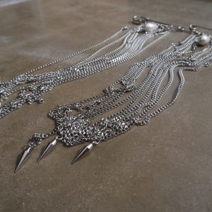 Statement accessoar med säkerhetsnålar, pärlor och kedjor fäst på kavaj